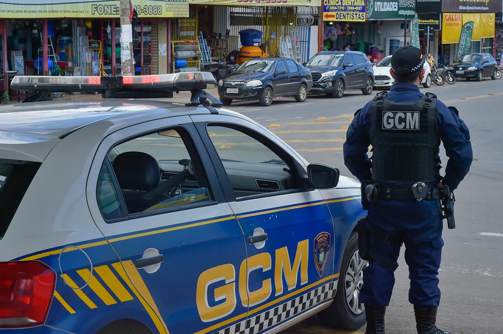 Agente da Guarda Civil de Aparecida patrulha região comercial ao lado de viatura, reforçando a segurança e presença preventiva nas ruas da cidade.