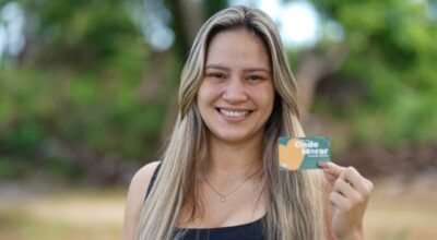 Foto de uma mulher segurando o cartão do benefício do Alguel social.