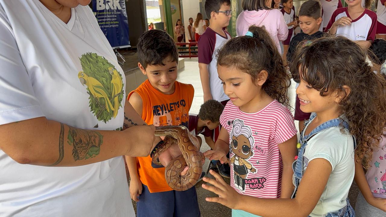 Crianças de uma escola municipal interagem com uma serpente durante atividade educativa da BRK.