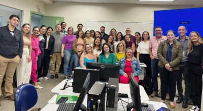 A imagem mostra um grupo de profissionais reunidos em sala de treinamento, posando para foto coletiva.